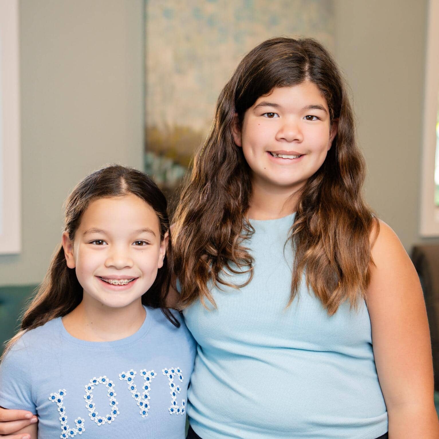 Two girls smiling together, one with braces, representing successful orthodontic treatment at Rambo Orthodontics.